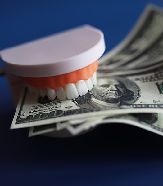 Artificial teeth chomping on several $100 bills