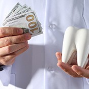 Dentist in white coat holding $100 bills in one hand and a large model tooth in the other