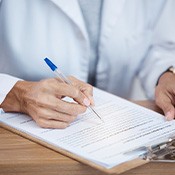 Person filling out paperwork on clipboard