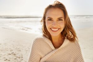 Woman with brown hair smiling at the beach