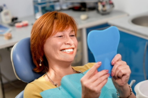 Patient admiring her dentures after her dentist cleaned them