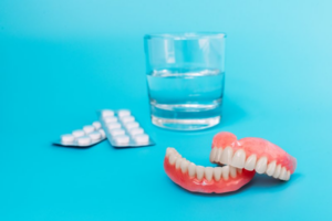 A pair of dentures and denture cleaning solution on a blue background